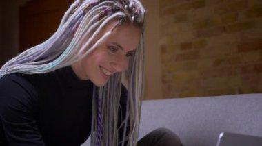 Dreadlocks ile genç çekici kafkas hipster kadın hareketli kamera ile Closeup çekim rahat bir daire içinde dizüstü bilgisayar da yazarak eller
