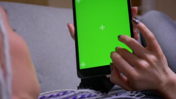 Крупним планом задній перегляд знімок молодої кавказької хіпстерки з дредлоками смс на планшеті з зеленим екраном з рекламою на ньому лежить на дивані в приміщенні — стокове відео