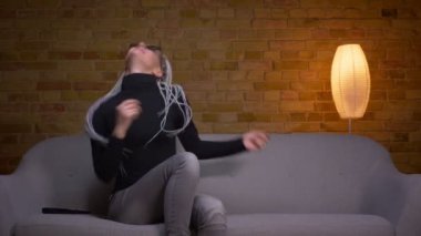 Genç çekici kafkas hipster kadın dans closeup ateş ve rahat bir dairede kanepede oturan Tv karaoke ile eğlenmek
