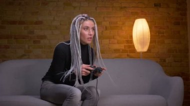 Tv'de video oyunları oynayan ve rahat bir dairede kanepede oturan bir düzeyde tamamlayarak mutlu oluyor genç çekici kafkas hipster kadın Closeup ateş