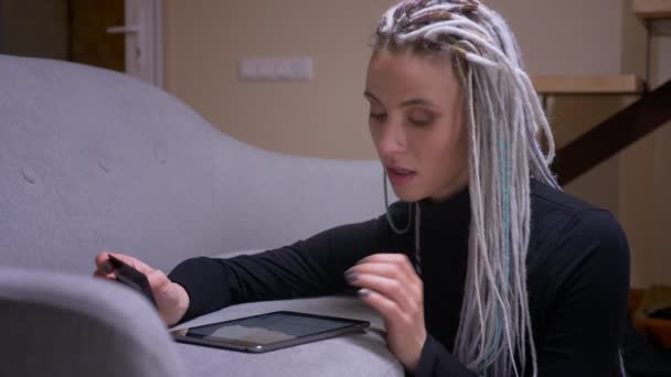 Close-up shoot van jonge aantrekkelijke Kaukasische hipster vrouw met dreadlocks online winkelen op de Tablet met creditcard glimlachen gelukkig binnenshuis in een gezellig appartement — Stockvideo