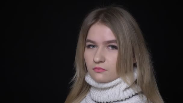 Close-up shoot van jonge mooie blanke vrouw in trui draaien en kijken naar camera met achtergrond geïsoleerd op zwart — Stockvideo