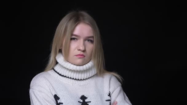 特写拍摄年轻漂亮的白种女性在毛衣点头说是看相机的背景孤立在黑色 — 图库视频影像