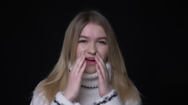 Closeup shoot of young pretty caucasian female in sweater being excited and smiling looking at camera with background isolated on black — Stock Video