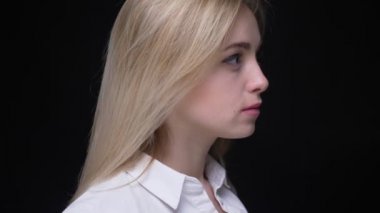 Beyaz gömlek li büyük gözlü Pretty sarışın iş kadını kameraya döner ve siyah arka plan üzerinde özenle saatler.