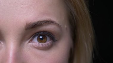 Siyah arka planda mutlu ve memnun olan kameraya genç iş kadını yakın çekim bir göz çekimi gülümsüyor.