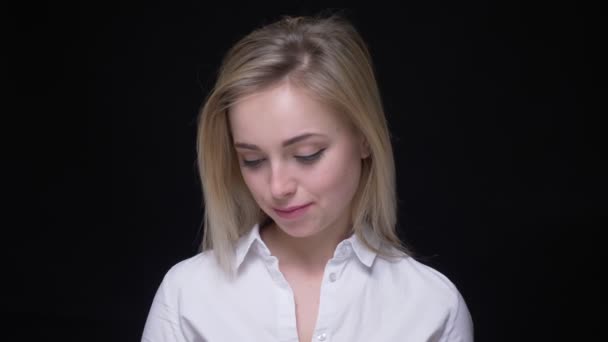 Красива і молода бізнес-леді в білій сорочці дивиться вниз сором'язлива на чорному тлі . — стокове відео