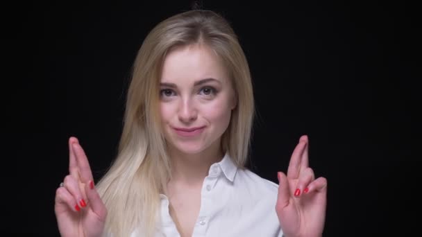 Vrolijke jonge zakenvrouw in wit overhemd bidden met gekruiste vingers op zwarte achtergrond. — Stockvideo