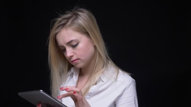 Giovane donna d'affari concentrata in camicia bianca che lavora con tablet si rivolge alla fotocamera in sorpresa su sfondo nero . — Video Stock