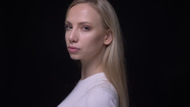 Gros plan portrait de jeune jolie blonde femelle tournant et regardant caméra avec fond isolé sur noir — Video