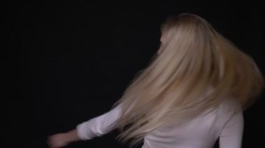 Siyah üzerine izole arka plan ile saçları çırpınan ve baştan çıkarıcı gülümseyen genç güzel sarışın kadın Closeup portre