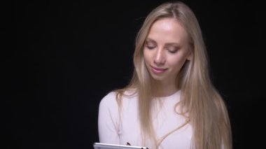 Tablet kullanarak genç güzel sarışın kadın Closeup portre ve siyah izole arka plan ile kamera bakarak yeşil renk ekran gösteren