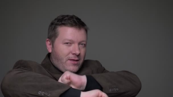 Retrato de alegre morena de mediana edad hombre de negocios en traje haciendo extrañas poses gestos ok signo sobre fondo gris . — Vídeos de Stock