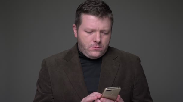 Brunetka středního věku obchodník v obleku pracuje s telefonem pozorně a ukazuje prstem na něm na šedém pozadí. — Stock video