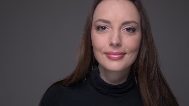 Close-up portret van volwassen aantrekkelijke Kaukasische vrouwelijke gezicht kijken naar camera met lachende gezichtsuitdrukking met achtergrond geïsoleerd op grijs — Stockvideo