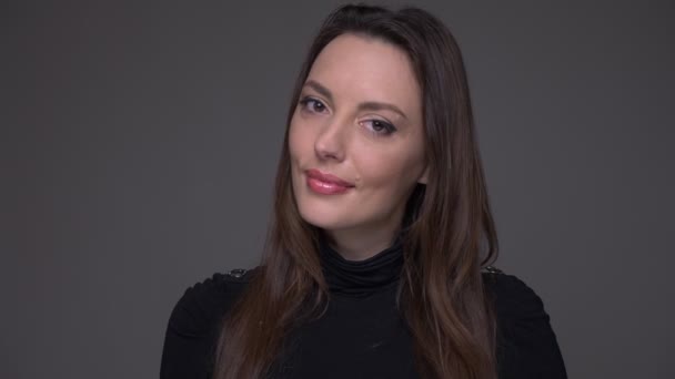 Närbild porträtt av vuxna attraktiva kaukasiska kvinnliga leende förföriskt tittar på kamera med bakgrund isolerad på grå — Stockvideo