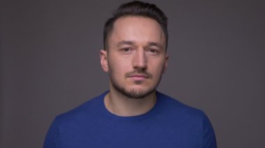 Gri izole arka plan ile kamera bakarak genç yakışıklı beyaz adamın Closeup çekim