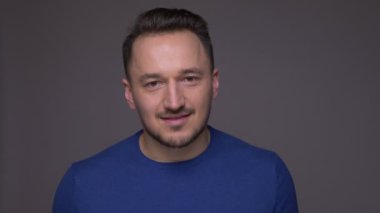 Kameraya bakan ve gri izole arka plan ile gülümseyen genç yakışıklı kafkas adam Closeup ateş