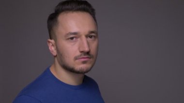 Genç yakışıklı beyaz adam dönüm ve gri izole arka plan ile kamera bakarak Closeup ateş