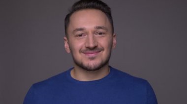 Genç yakışıklı beyaz adam utangaçlık ile gülümseyen Closeup çekim gri izole arka plan ile kamera bakarak