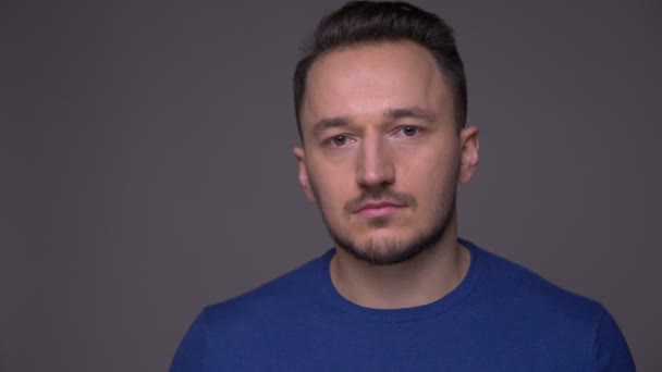 Closeup shoot of young handsome caucasian man being sad and depressed looking at camera with background isolated on gray — Stock Video