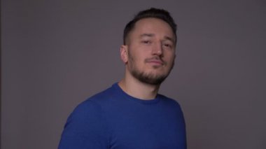 Genç yakışıklı beyaz adam güvenle gülümseyen ve gri izole arka plan ile kamera bakarak Closeup ateş