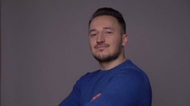 Genç yakışıklı beyaz adam kolları göğüs üzerinde geçti ve gri izole arka plan ile kameraya bakarak güvenle gülümseyen closeup ateş