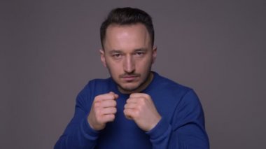Genç yakışıklı beyaz adam bir boksör elleri gri izole arka plan ile kameraya bakarak tekme olmak Closeup ateş
