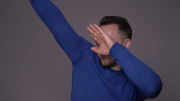 Closeup shoot of young handsome caucasian man dabbing with confidence in front of the camera with background isolated on gray — Stock Video