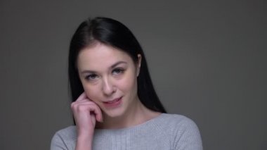 Genç oldukça beyaz kadın baştan çıkarıcı gülümseyen ve gri izole arka plan ile kameraya bakarak Closeup ateş