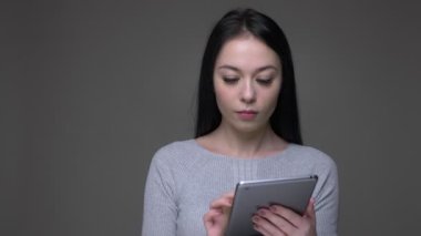 Tablet kullanarak genç güzel esmer kafkas kadın Closeup ateş ve gri izole arka plan ile kameraya yeşil ekran gösteren