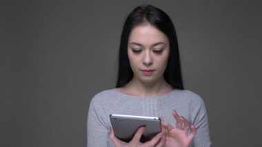 Tablet kullanarak genç güzel esmer kafkas kadın Closeup ateş ve gri izole arka plan ile kameraya yeşil renk ekran gösteren