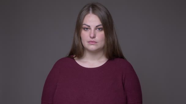 Closeup portarit of young overweight caucasian female looking at camera with background isolated on gray — Stock Video