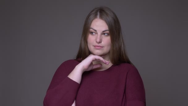 Close-up portarit van jonge overgewicht Kaukasische vrouwelijke glimlachend en kijken naar camera met achtergrond geïsoleerd op grijs — Stockvideo