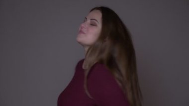 Genç kilolu beyaz kadın yakın çekim portarit saçları çırpınan ve neşeyle gülen kamera yayan arka plan gri izole ile