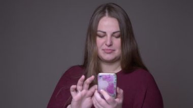 Gri izole arka plan ile telefonda genç kilolu beyaz kadın mesajlaşma Closeup portarit