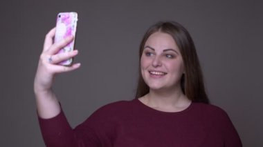 Genç kilolu beyaz kadın gri izole arka plan ile telefonda selfie çekerek Closeup portarit