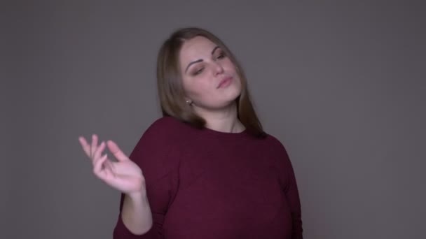 Close-up portarit van jonge overgewicht Kaukasische vrouwelijke dansen met vreugde kijken naar camera met achtergrond geïsoleerd op grijs — Stockvideo