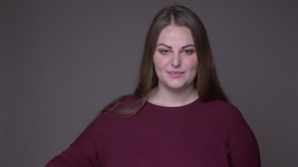 Närbild portarit av unga överviktiga kaukasiska kvinnlig gest OK handsign tittar på kamera med bakgrund isolerad på grå — Stockvideo
