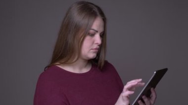 Genç kilolu beyaz kadın arka plan gri izole ile tablet mesajlaşma Closeup portarit