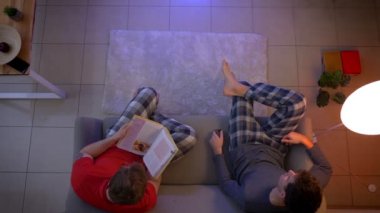 Uzaktan kumanda ile Tv programlarını değiştirme ve oturma odasında kitap okuma pijama arkadaşlarının en iyi çekimi.