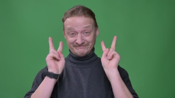 Portret van middelbare leeftijd man met baard gebaren stuk teken om aan te tonen dat alles goed is op groene achtergrond. — Stockvideo
