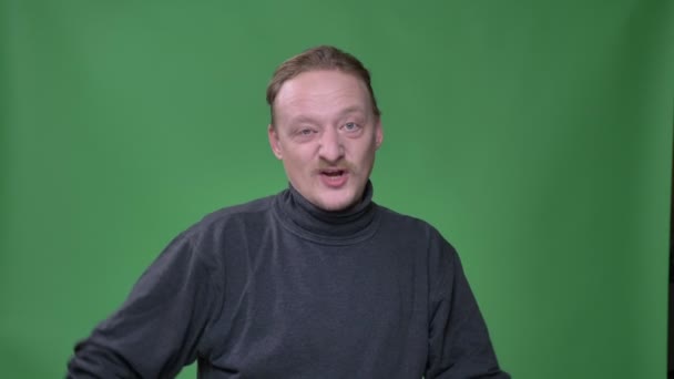 Porträt eines Mannes mittleren Alters mit Bart, um zu demonstrieren, dass auf grünem Hintergrund alles cool ist. — Stockvideo