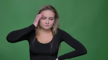 Baş ağrısı muzdarip siyah bluz üzgün genç model portresi yeşil arka planda masaj yapar.