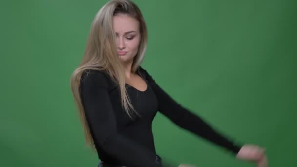 Porträt einer entzückten Geschäftsfrau in schwarzer Bluse, die fröhlich und seltsam auf grünem Hintergrund tanzt. — Stockvideo