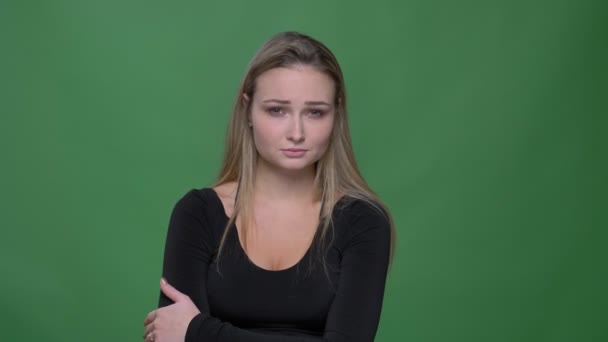 Porträtt av deprimerad ung modell i svart blus tittar sorgligt in i kameran med grön bakgrund. — Stockvideo