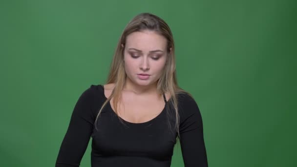 Портрет грустной молодой модели в черной блузке, страдающей от головной боли на зеленом фоне . — стоковое видео