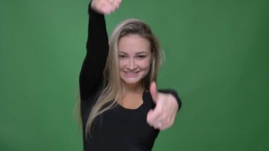 Siyah bluzlu iş kadını, yeşil arka planda kameraya beğeni ve saygı göstermek için parmak-up işaretleri gesturing.