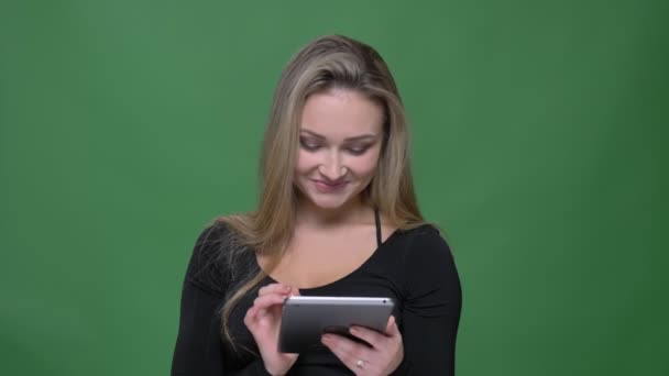 Zakenvrouw in zwarte blouse kijken naar Tablet glimlacht op een groene achtergrond. — Stockvideo