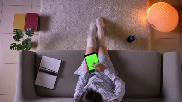 Крупный план верхней съемки молодых привлекательных женщин, печатающих на планшете с зеленым хроматическим экраном сидя на диване в милых носках — стоковое видео